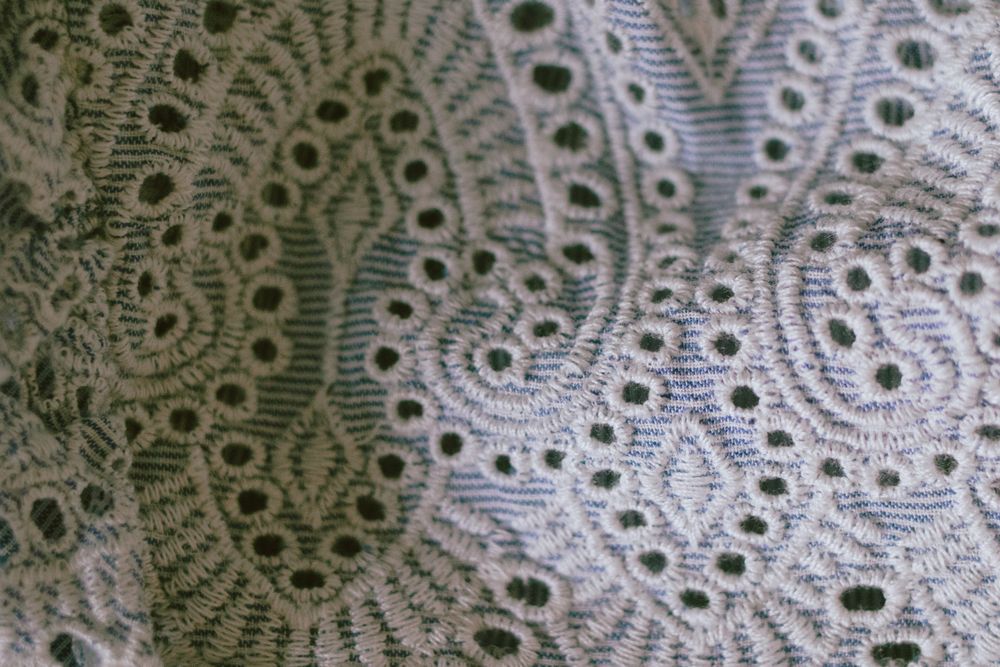 Close-up of floral eyelet cutwork with embroidered edges and open patterns in fabric