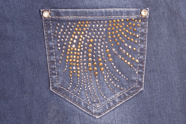 Silver and gold rhinestone patterns on the back pocket of blue denim jeans